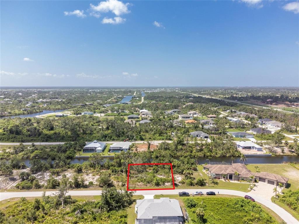 An aerial view shows a vacant residential lot outlined in red along a canal — 9602 GAZANIA DRIVE, PORT CHARLOTTE, FL