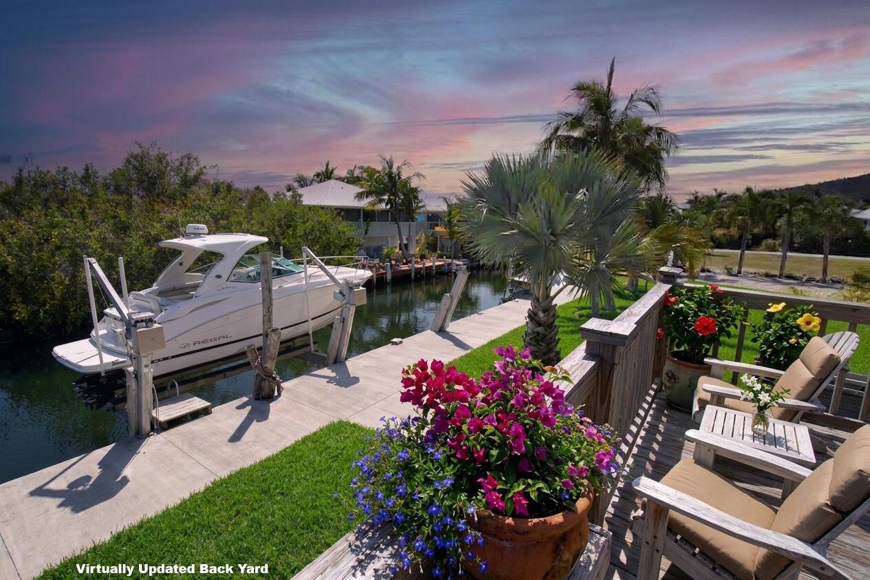 A boat on a lift sits in a canal next to a grassy backyard patio — 22920 Privateer Drive, FL 33042, FL