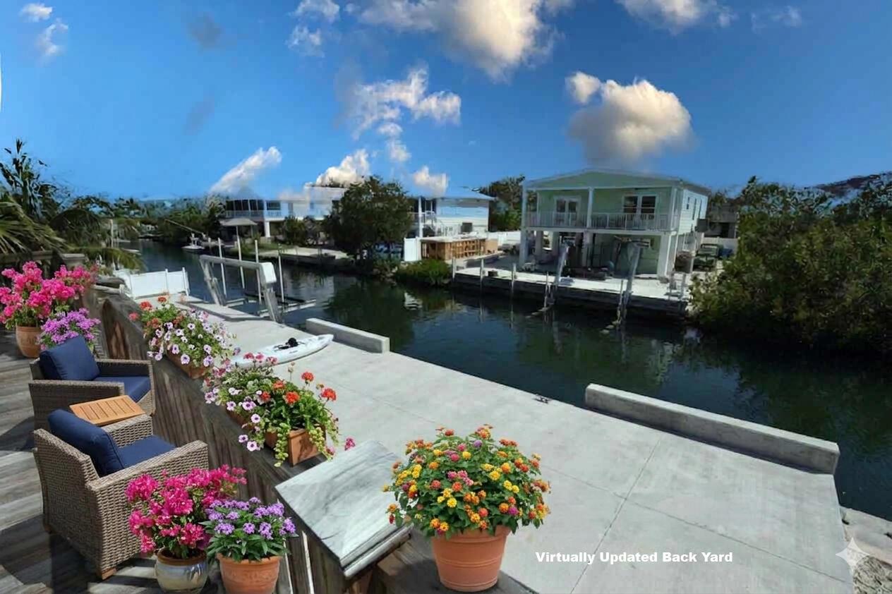 A concrete patio overlooks a canal with houses and a boat dock in the background — 22920 Privateer Drive, FL 33042, FL