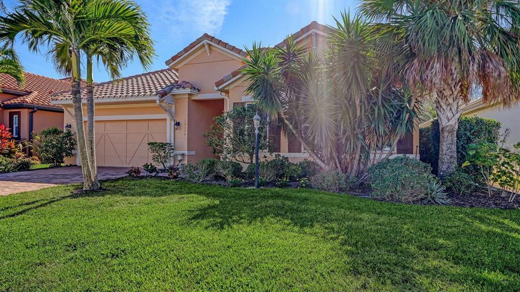A single-story house with a tan stucco exterior, a tiled roof, and a palm-lined lawn — 10310 EASTWOOD DRIVE, BRADENTON, FL
