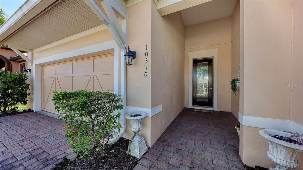 The exterior view shows a house entrance with a garage, paved walkway, and front door — 10310 EASTWOOD DRIVE, BRADENTON, FL
