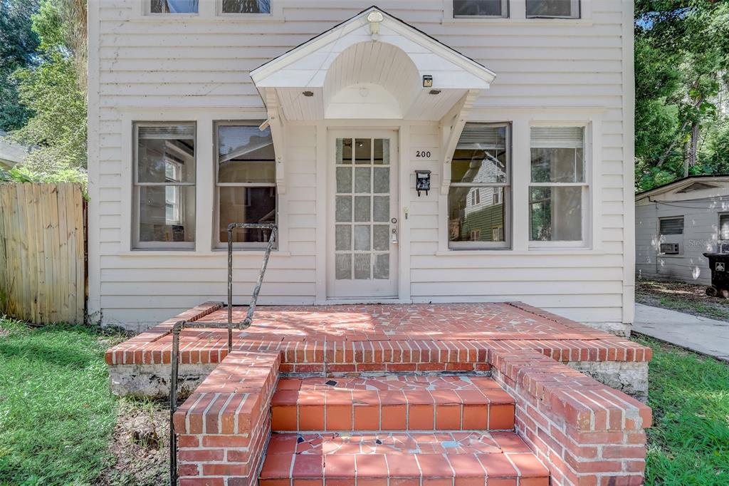 A two-story house with white siding, a brick porch, and a glass-paneled front door — 200 & 200 1/2 HIBISCUS COURT, ORLANDO, FL