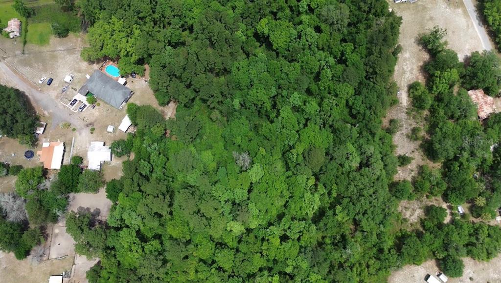 An aerial view shows a wooded lot adjacent to a house with a swimming pool — MARSHALL LANE, GREEN COVE SPRINGS, FL