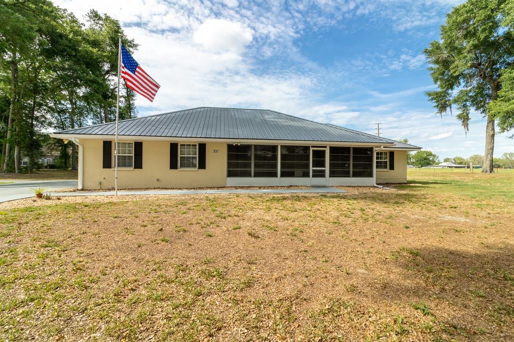A single-story house with a metal roof and screened porch sits on a grassy lot — 300 SW BRIGHTON COURT, FORT WHITE, FL
