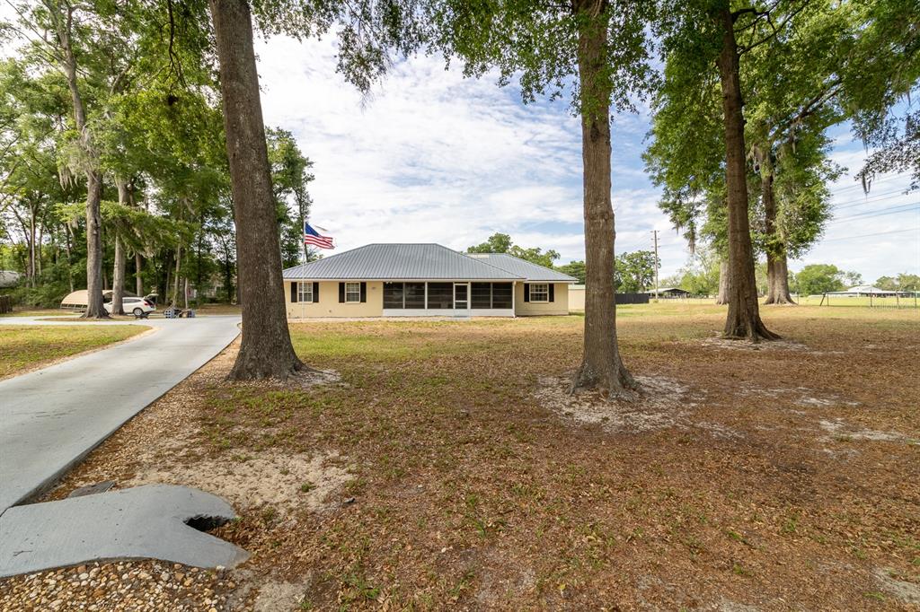 A single-story house with a metal roof and a screened-in porch overlooks a grassy yard — 300 SW BRIGHTON COURT, FORT WHITE, FL