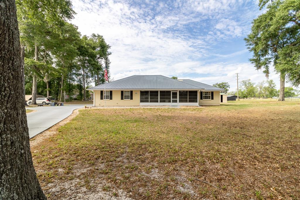 A single-story house with a metal roof and a detached garage sits on a lawn — 300 SW BRIGHTON COURT, FORT WHITE, FL