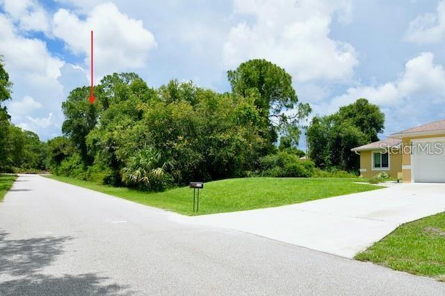 A paved road leads to a vacant, tree-covered lot next to a house with a driveway — 2328 REDFERN STREET, PORT CHARLOTTE, FL