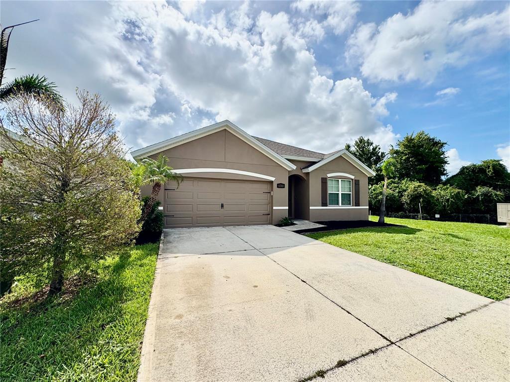 A single-story house with a tan stucco exterior, a two-car garage, and a concrete driveway — 4340 PAGOSA SPRINGS CIRCLE, MELBOURNE, FL