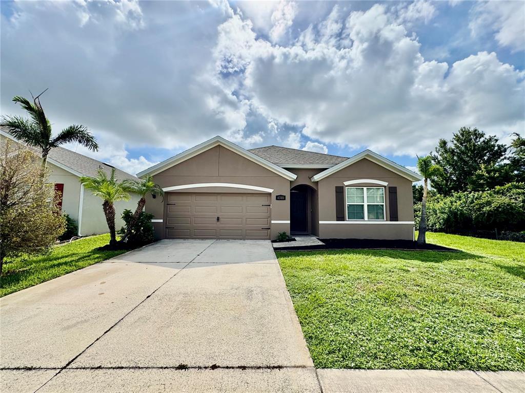 A single-story house with a tan stucco exterior, a two-car garage, and a concrete driveway — 4340 PAGOSA SPRINGS CIRCLE, MELBOURNE, FL