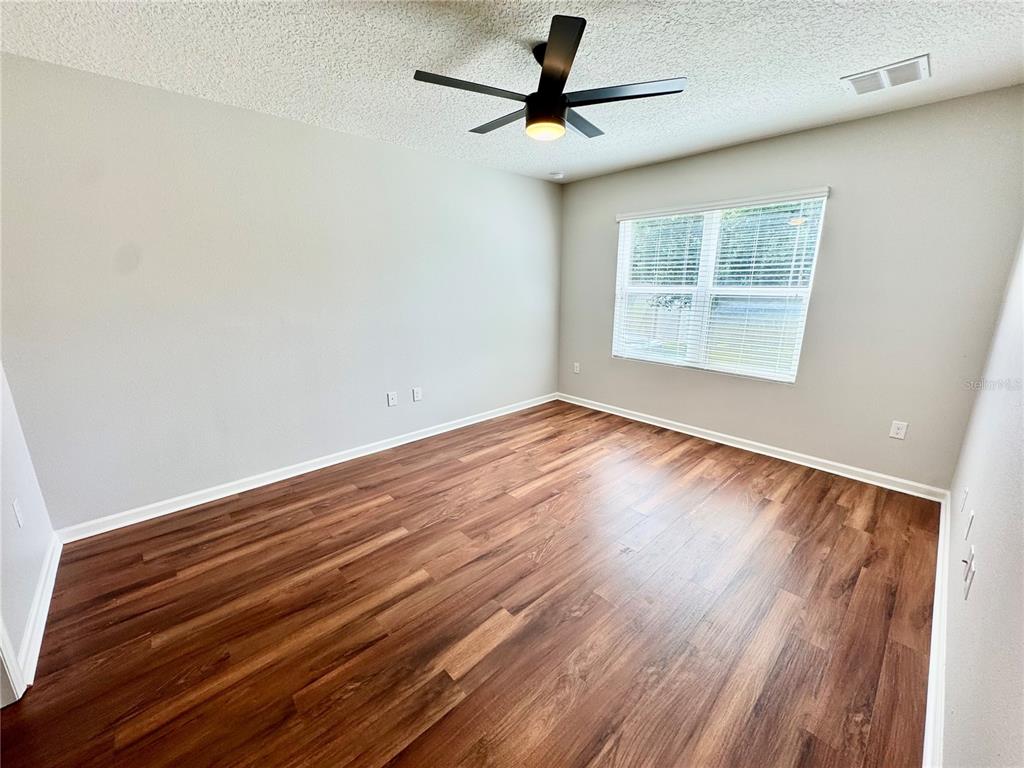 An empty bedroom features light gray walls, dark wood-look flooring, and a ceiling fan — 4340 PAGOSA SPRINGS CIRCLE, MELBOURNE, FL