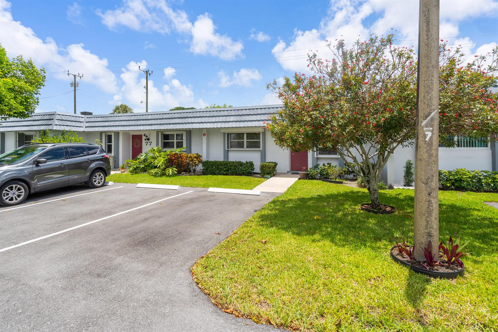 A single-story residential building with a parking lot, a lawn, and a flowering tree — 2886 Fernley Drive E # 76, West Palm Beach FL 33415, WEST PALM BEACH, FL