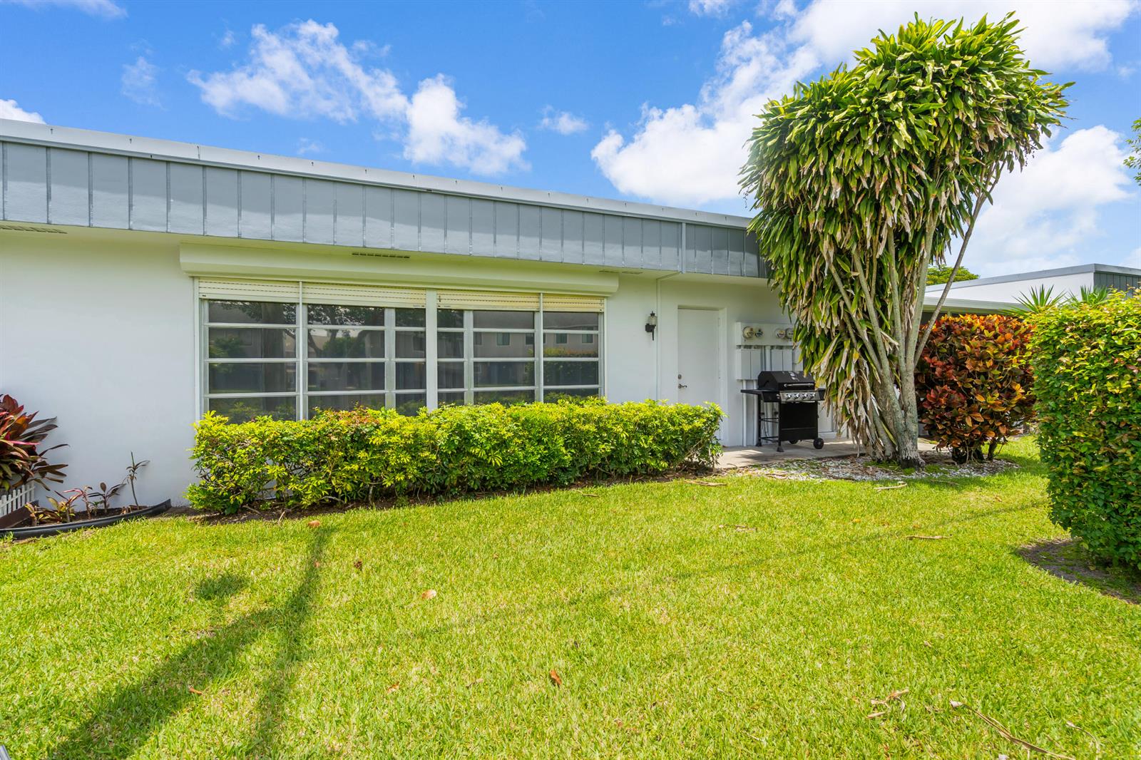 A white single-story building exterior features a large window, a door, and a grill — 2886 Fernley Drive E # 76, West Palm Beach FL 33415, WEST PALM BEACH, FL