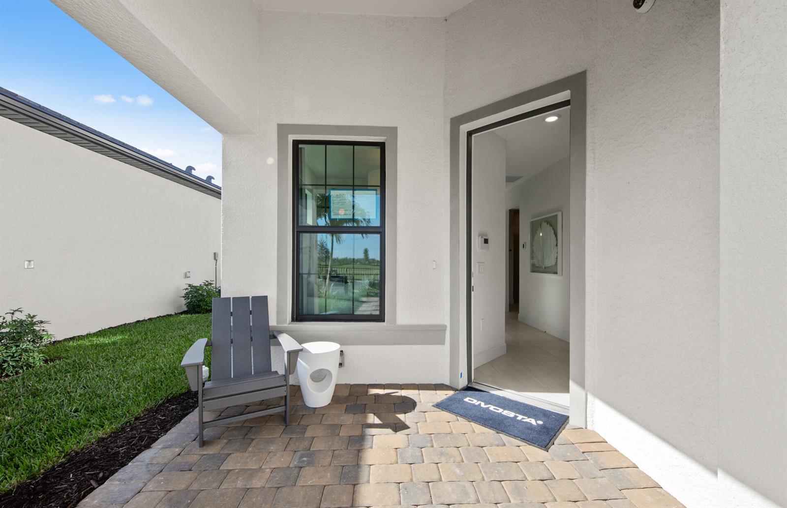 A gray Adirondack chair and white side table sit on a paved patio entrance — 2114 Sequoia, Naples FL 34120, NAPLES, FL