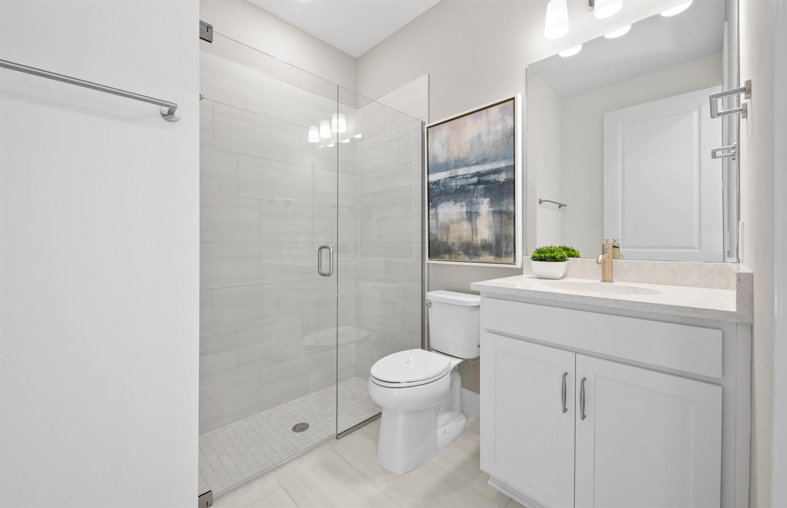 A modern bathroom features a glass-enclosed walk-in shower, a white vanity, and a toilet — 2114 Sequoia, Naples FL 34120, NAPLES, FL
