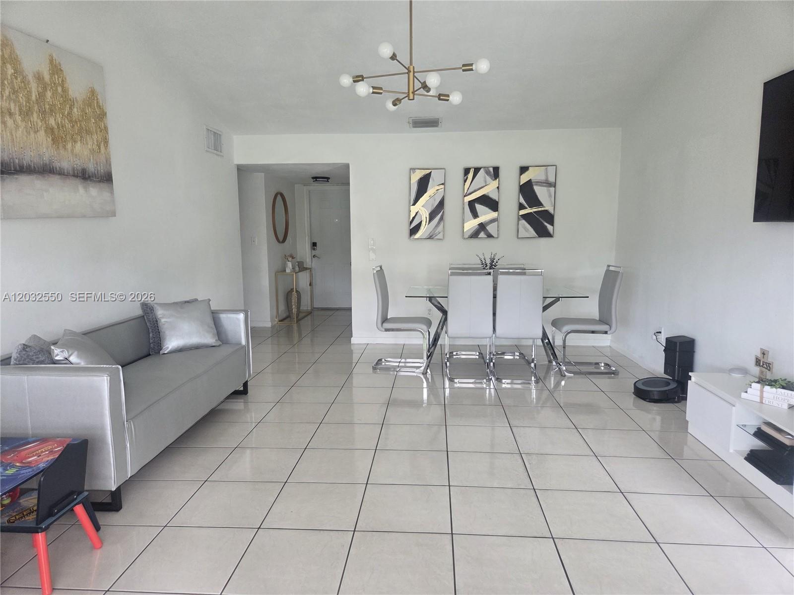 A living and dining area features white tile floors, a silver sofa, and modern decor — 11871 SW 123rd Pl, Miami FL 33186, MIAMI, FL