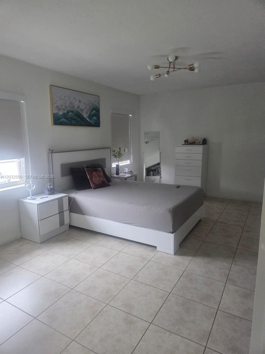 A bedroom features a bed with a grey comforter, white furniture, and tiled flooring — 11871 SW 123rd Pl, Miami FL 33186, MIAMI, FL
