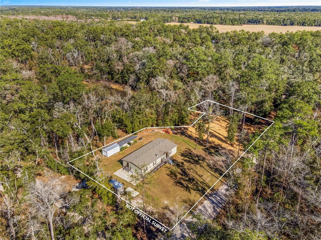 An aerial view shows a house and a shed on a wooded lot — 7970 SW 14TH PLACE, BELL, FL