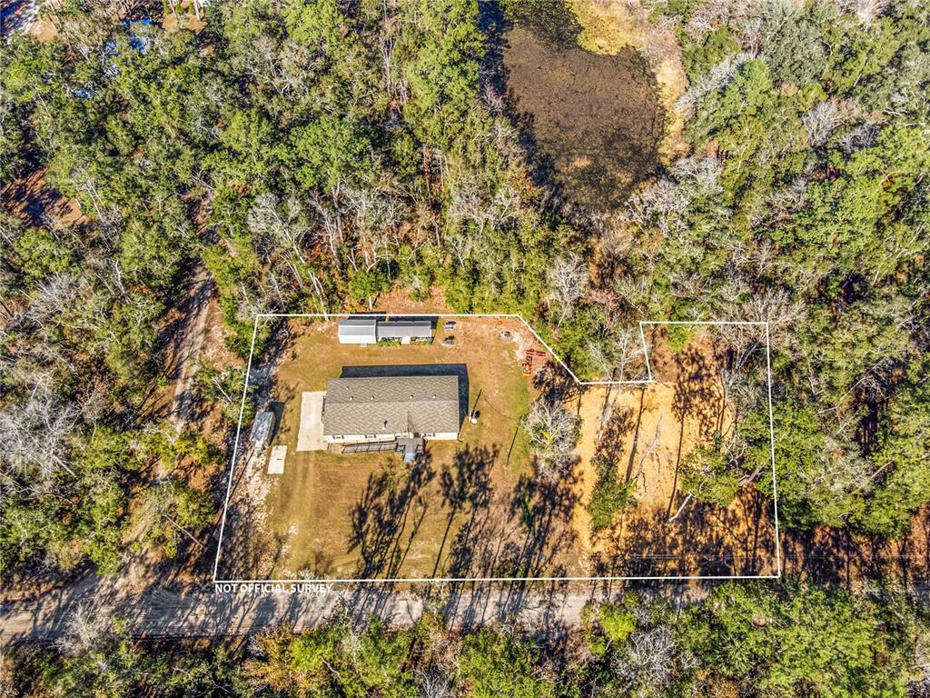 An aerial view shows a house and a detached structure on a wooded lot — 7970 SW 14TH PLACE, BELL, FL