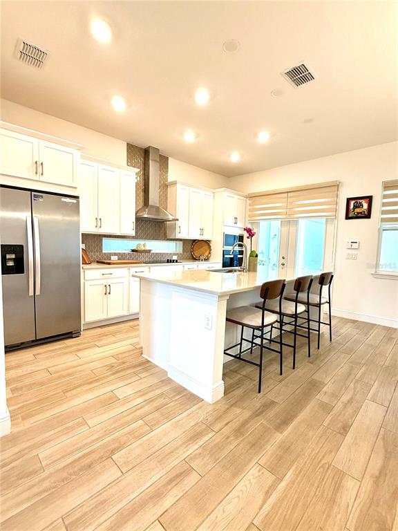 A modern kitchen features white cabinetry, a stainless steel refrigerator, and a central island — 9922 RODBELL STREET, ORLANDO, FL