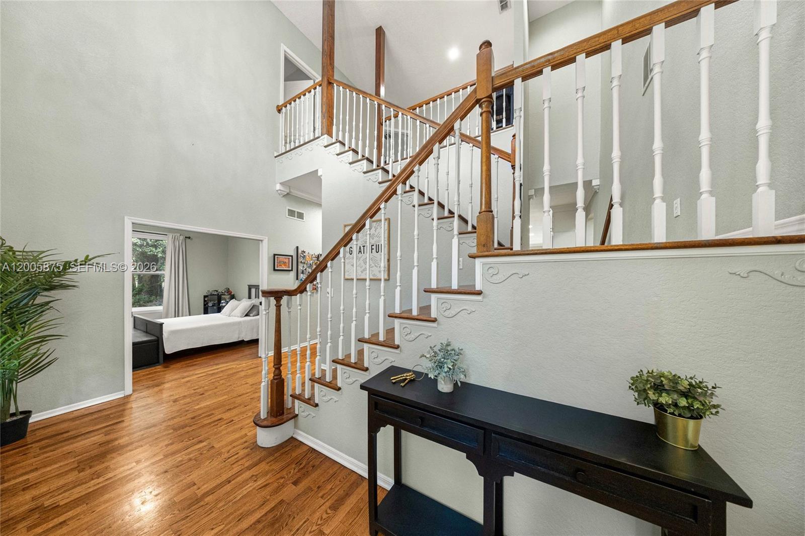 A foyer features a wooden staircase with white balusters, hardwood floors, and a black console table — 9175 SE 7th Avenue Rd, Ocala FL 34480, OCALA, FL