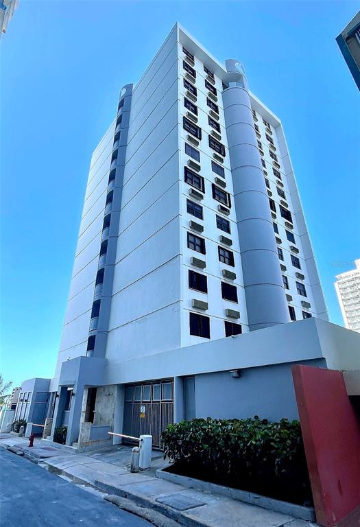 A low-angle exterior view of a tall, white apartment building with a gated entrance — 7 EARLE STREET UNIT 901, SAN JUAN, PR