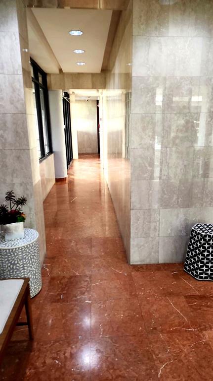 A hallway with red marble flooring and light-colored tiled walls leads toward a bright doorway — 7 EARLE STREET UNIT 901, SAN JUAN, PR