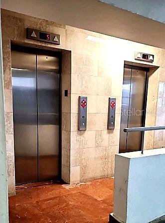 Two stainless steel elevators are set into a tiled wall in a building hallway — 7 EARLE STREET UNIT 901, SAN JUAN, PR