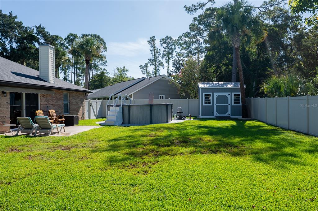 A backyard features a brick house, a patio, and an above-ground pool with equipment — 6 BRADLEY PLACE, PALM COAST, FL