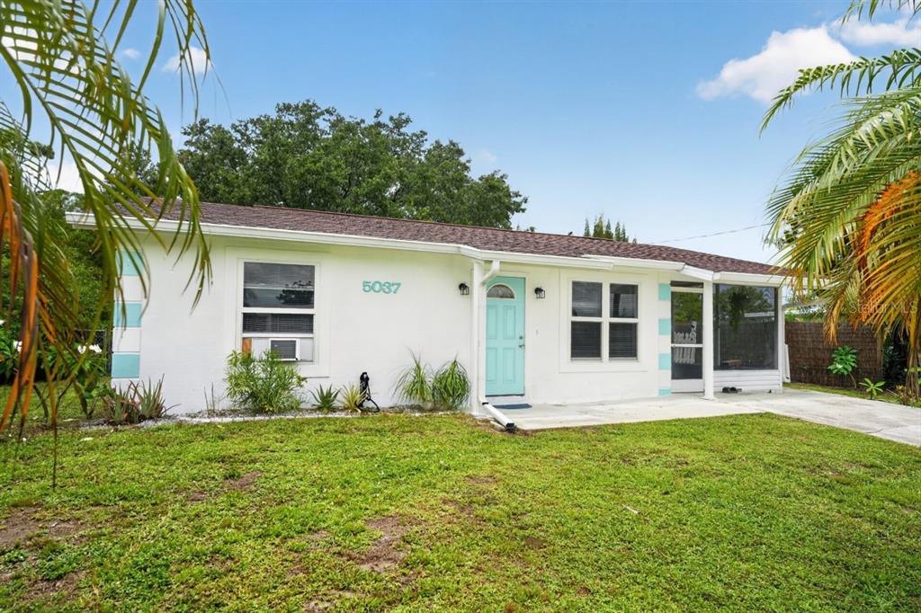 A white single-story house with a light blue front door and a grassy front yard — 5037 BULLARD STREET, NORTH PORT, FL