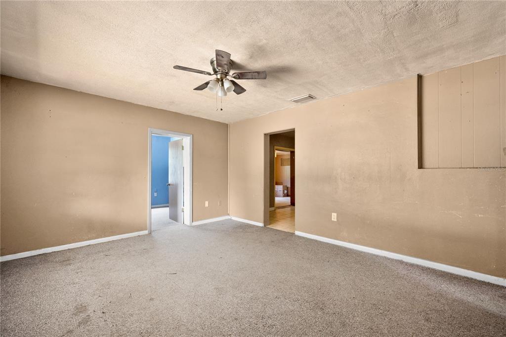 An empty room with beige walls, gray carpeting, a ceiling fan, and two doorways — 124 CENTER STREET, WINTER HAVEN, FL