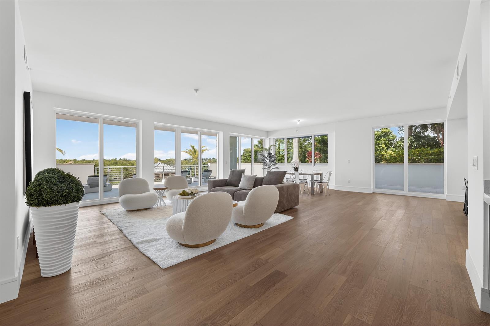 A bright, open-concept living room features hardwood floors, white walls, and large sliding glass doors — 1 S Coastal Way # 201, Jupiter FL 33477, JUPITER, FL