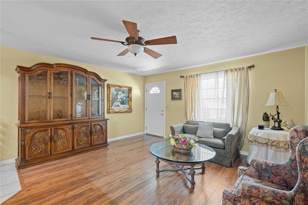 A living room features wood-look flooring, a large hutch, a sofa, and a ceiling fan — 38732 TALL DRIVE, ZEPHYRHILLS, FL