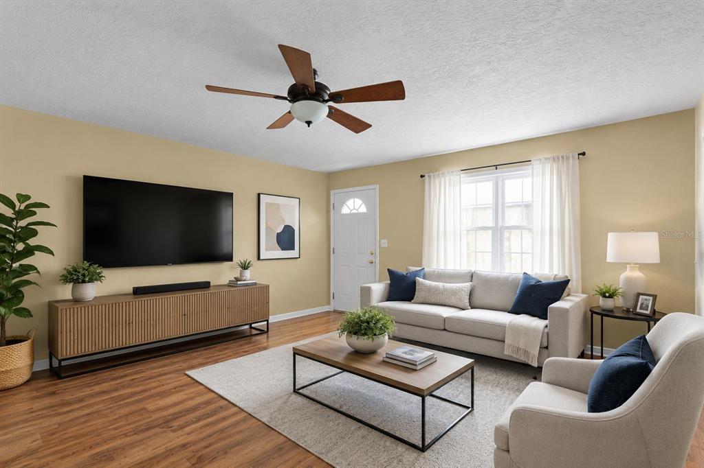 A living room features a television, media console, sofa, armchair, and wood-look flooring — 38732 TALL DRIVE, ZEPHYRHILLS, FL