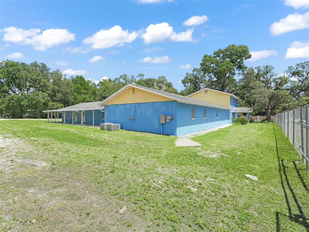 A blue and yellow one-story building sits on a grassy lot with a chain-link fence — 9475 SE 35TH COURT, OCALA, FL