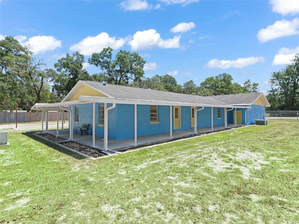 A blue, single-story house with a yellow gable and a long, covered concrete porch — 9475 SE 35TH COURT, OCALA, FL