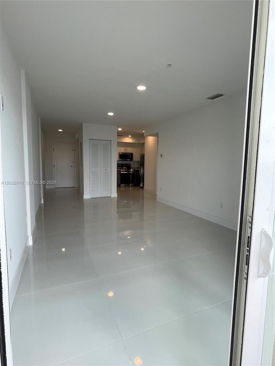 This interior view shows an open-concept living area with white tile floors and a kitchen — 10950 NW 82nd St # 207, Doral FL 33178, DORAL, FL