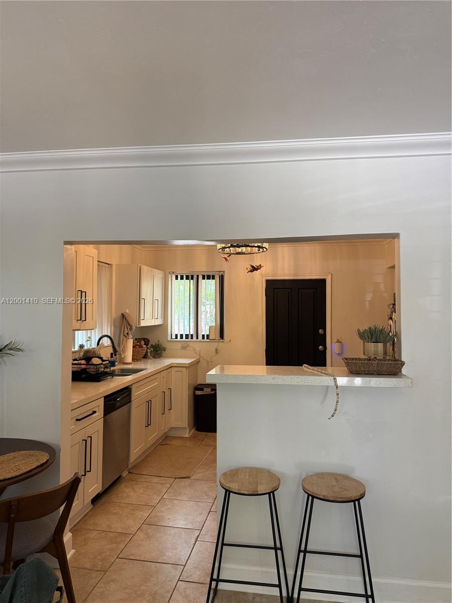 A kitchen with white cabinets, light countertops, and a breakfast bar with two stools — 5530 NW Miami Ct, Miami FL 33127, MIAMI, FL