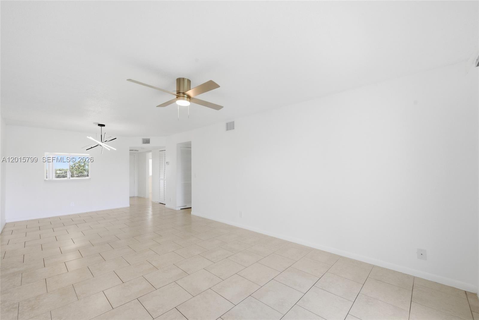 A bright, empty room features white walls, light-colored tile flooring, and two ceiling fixtures — SUNRISE, FL