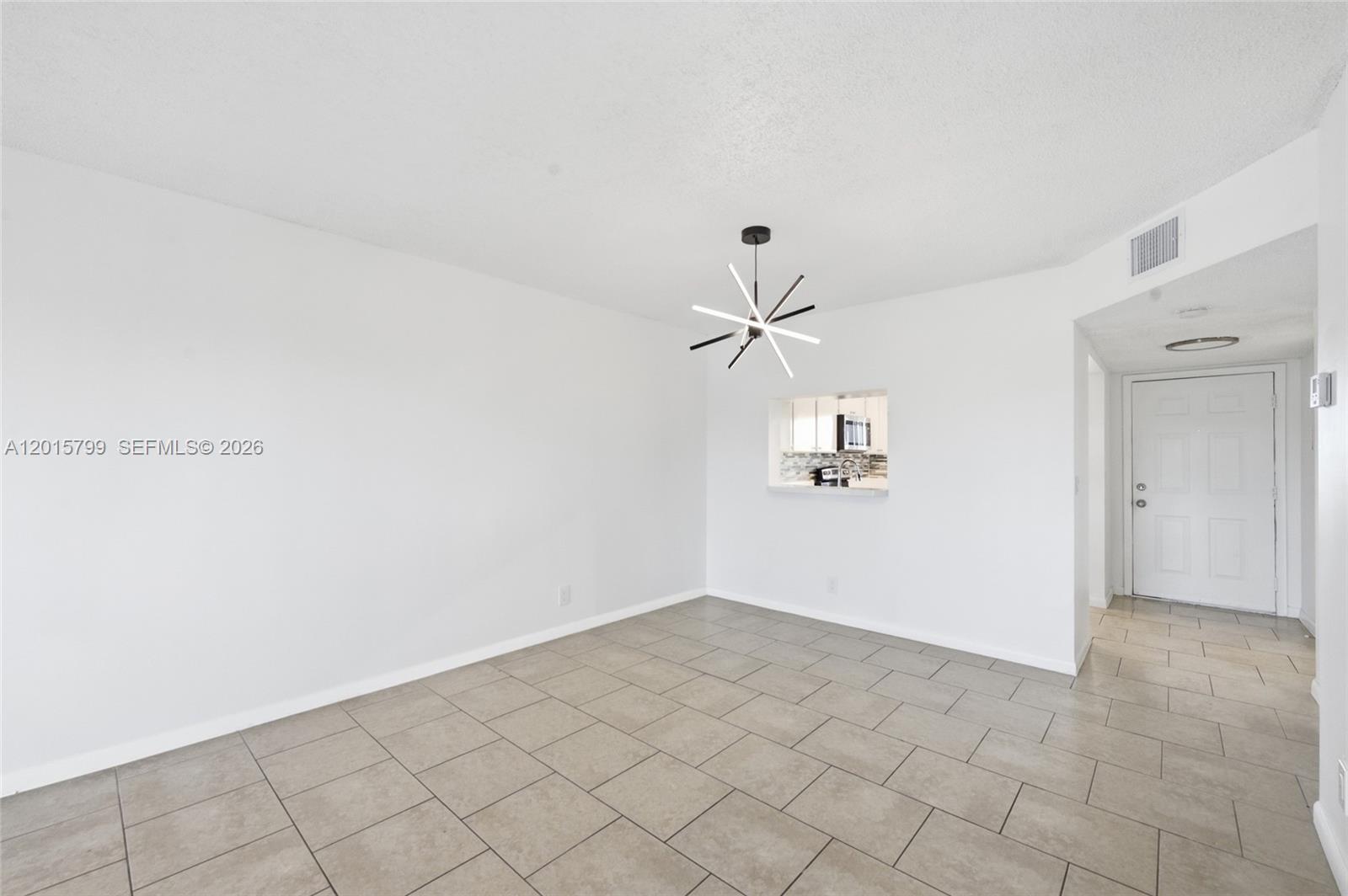 A dining area features white walls, light-colored tile flooring, and a modern sputnik chandelier — SUNRISE, FL