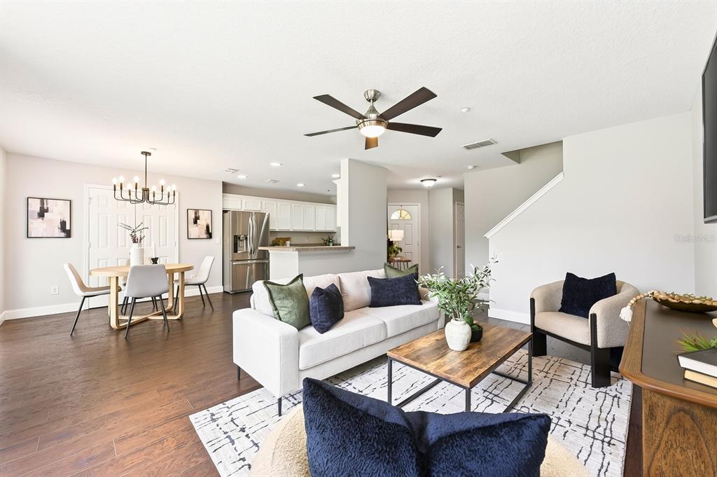 An open-concept living and dining area features hardwood floors, a neutral sofa, and a kitchen — 13765 GOLDEN RUSSET DRIVE, WINTER GARDEN, FL