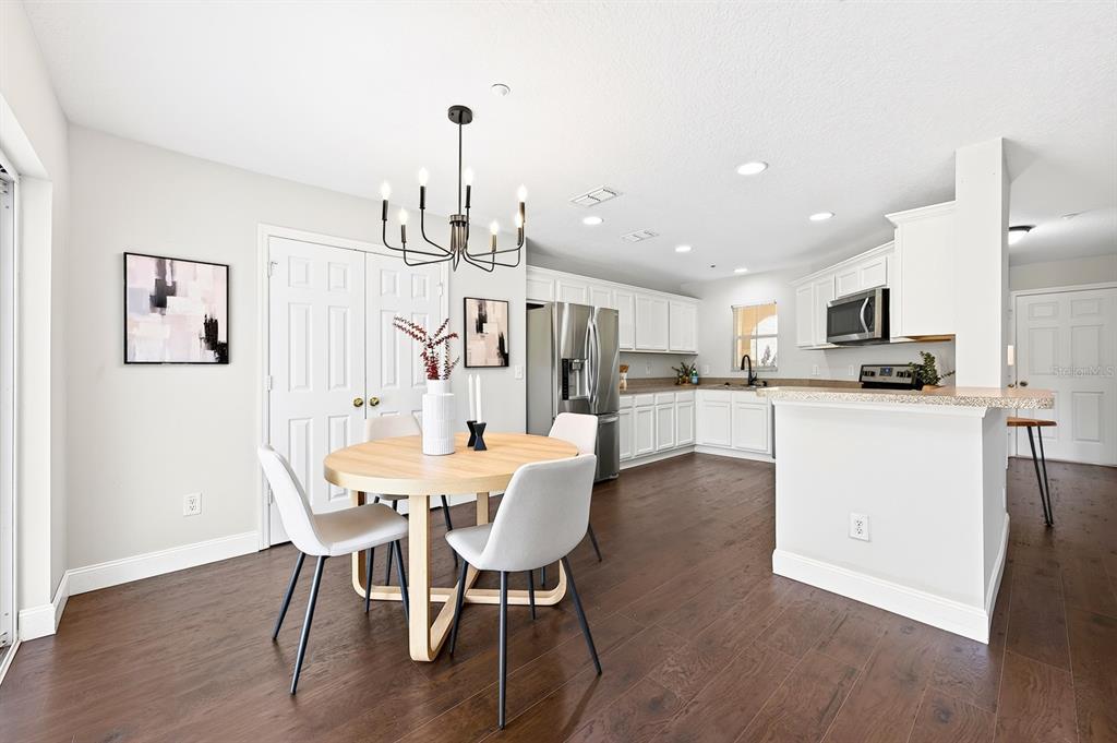 A dining area with a round table and chandelier opens into a white kitchen — 13765 GOLDEN RUSSET DRIVE, WINTER GARDEN, FL