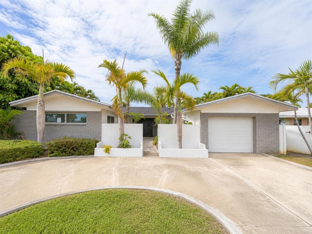 A mid-century modern living room features a green sectional, orange armchairs, and a black fireplace — 243 3RD STREET W, TIERRA VERDE, FL