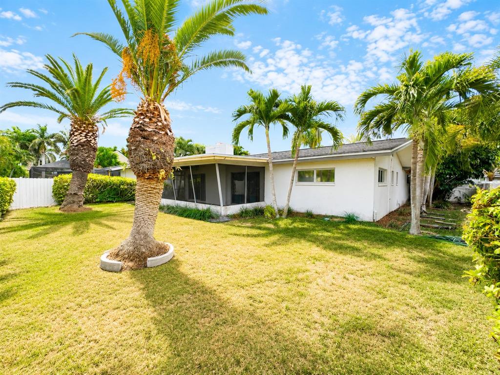 A dining room features a round wooden table, green chairs, and a mid-century modern sideboard — 243 3RD STREET W, TIERRA VERDE, FL