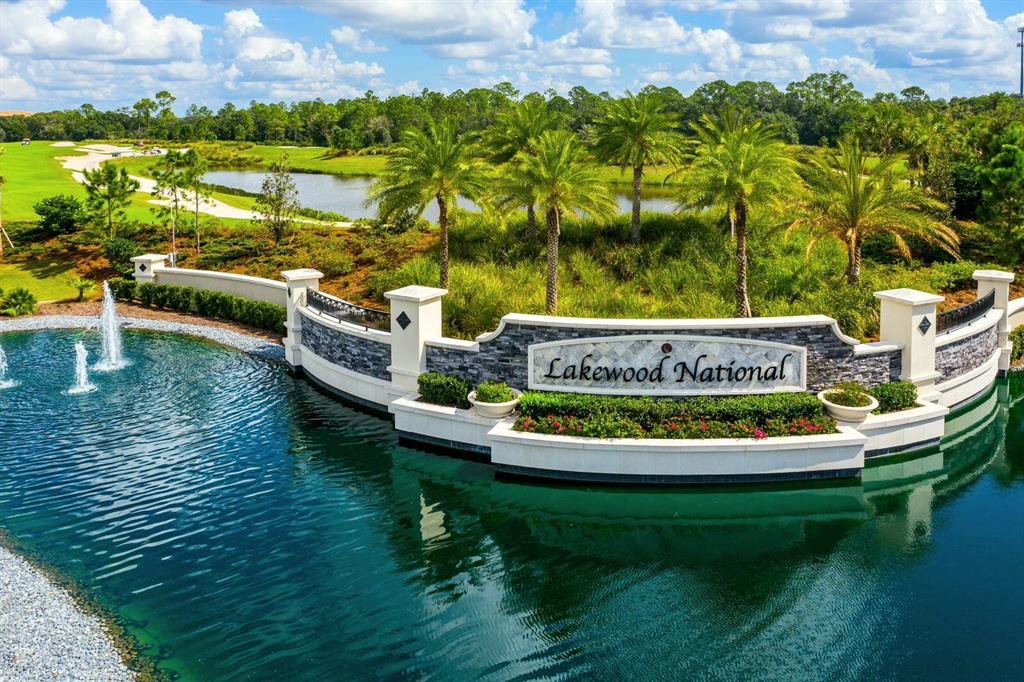 An aerial view shows the Lakewood National entrance sign surrounded by a pond and palm trees — 17510 GAWTHROP DRIVE UNIT 104, BRADENTON, FL