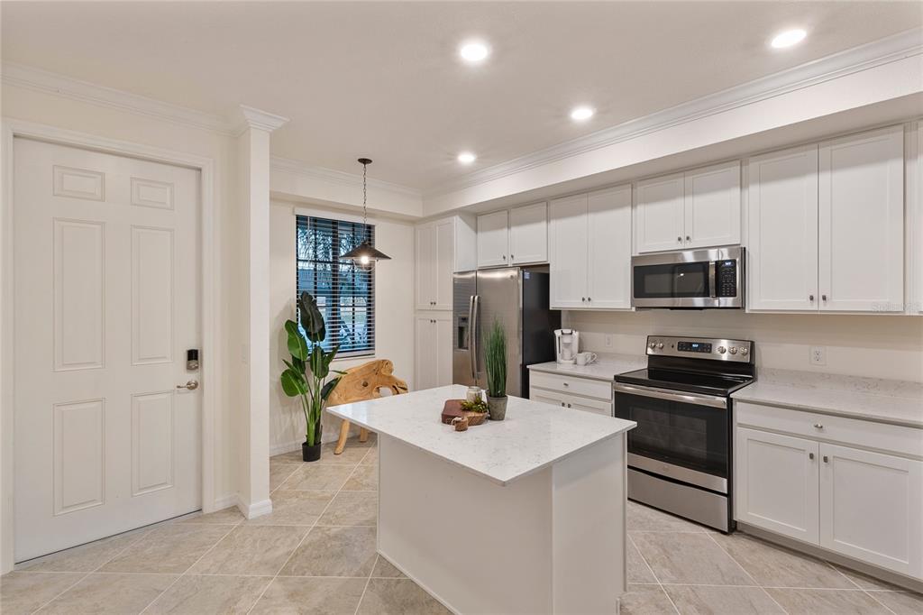A kitchen with white cabinets, stainless steel appliances, a center island, and tile flooring — 17510 GAWTHROP DRIVE UNIT 104, BRADENTON, FL