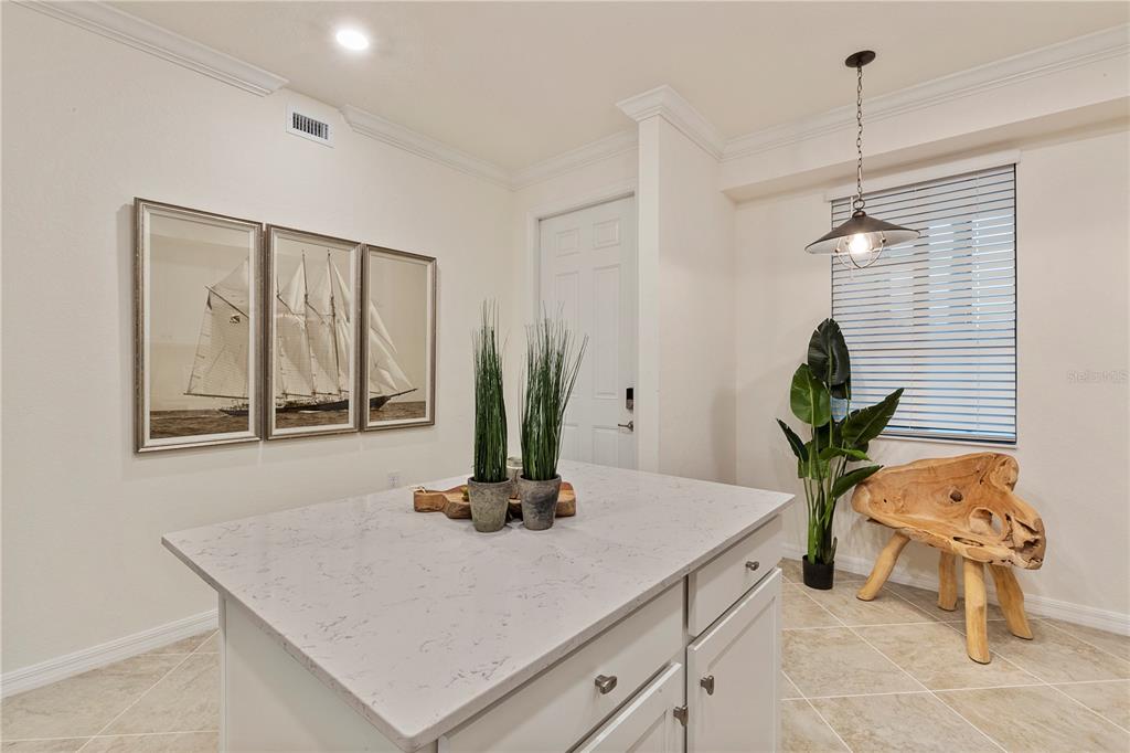 A kitchen island with a quartz countertop sits in a room with tile flooring — 17510 GAWTHROP DRIVE UNIT 104, BRADENTON, FL