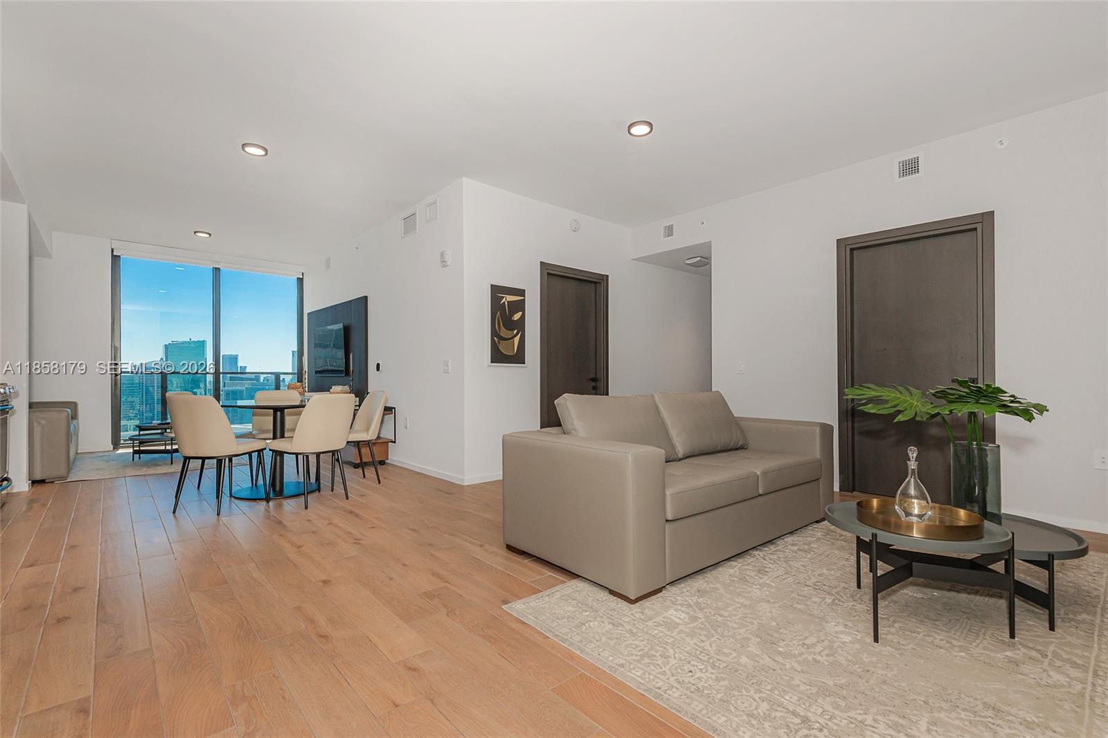 A modern living and dining area features light wood floors, a gray sofa, and floor-to-ceiling windows — 398 NE 5th St # 4417, Miami FL 33132, MIAMI, FL