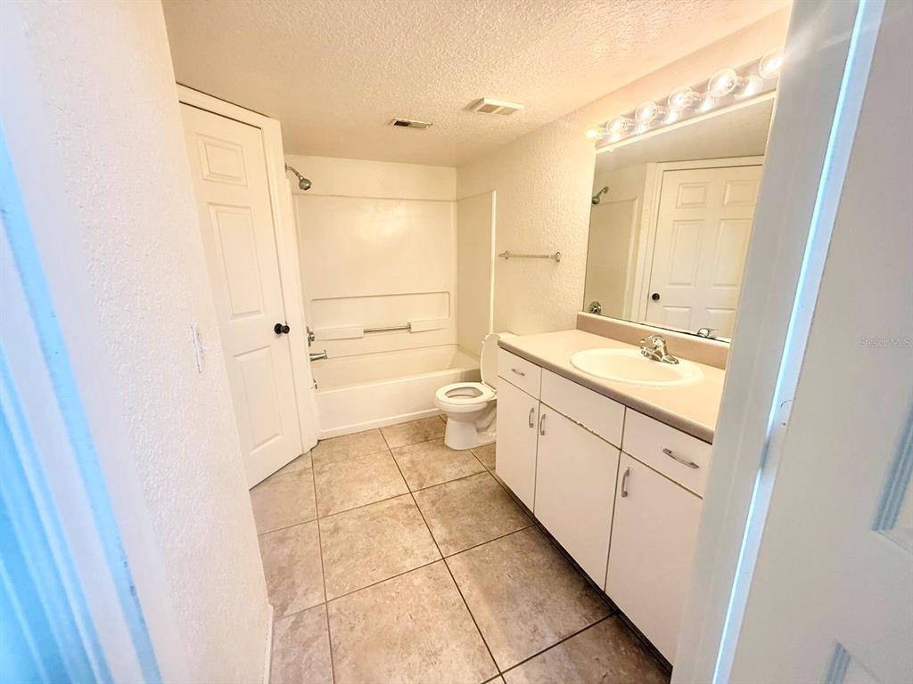 A bathroom features a white vanity, a toilet, and a shower-tub combination with tiled flooring — 2201 METROPOLITAN WAY UNIT 1423, ORLANDO, FL