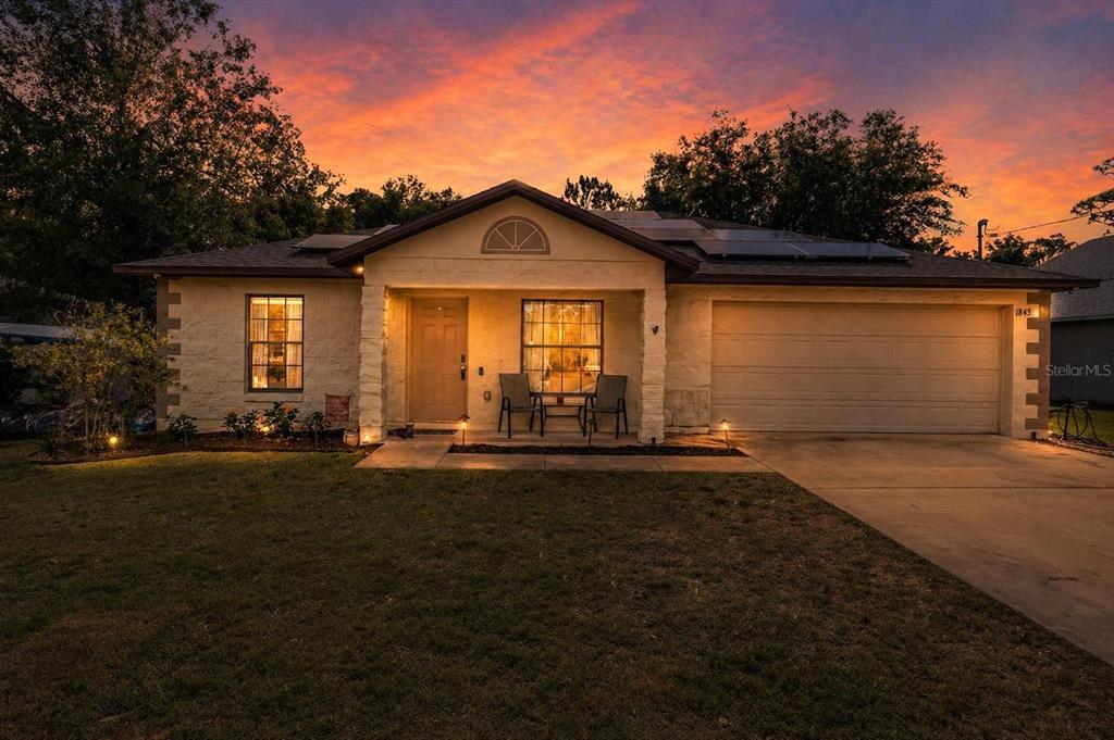 A single-story house with a tan exterior, a two-car garage, and solar panels on the roof — 1845 6TH AVENUE, DELAND, FL