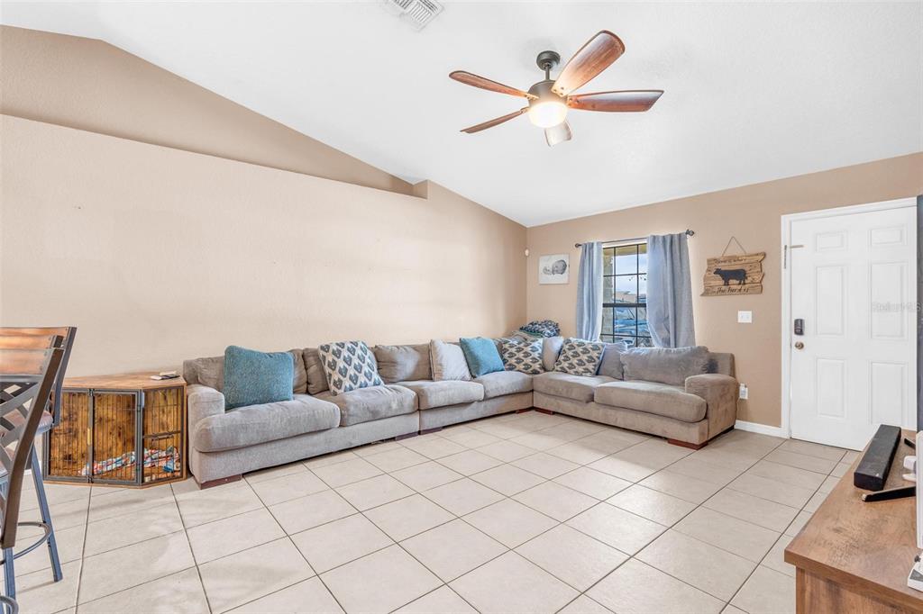 A living room features a large sectional sofa, tiled floors, and a vaulted ceiling — 1845 6TH AVENUE, DELAND, FL